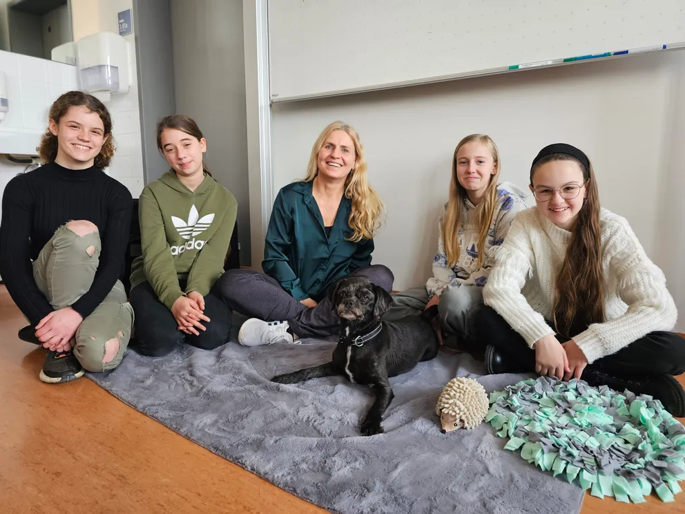 Gruppe von Schülern mit Lehrkraft und Schulhund Mikey im Klassenzimmer