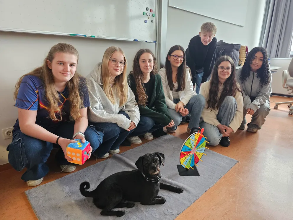 Gruppe von Schülern im Klassenzimmer mit Schulhund Mikey